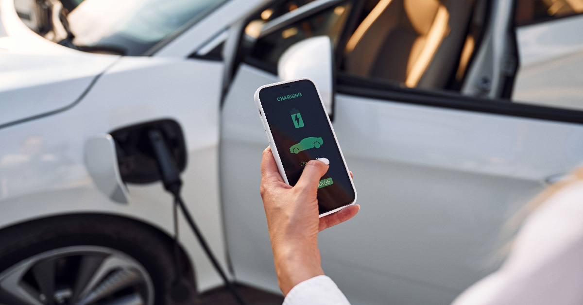 A person controlling electric vehicle charging using a smart phone app