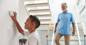 A child adjusts a smart thermostat while a parent looks on